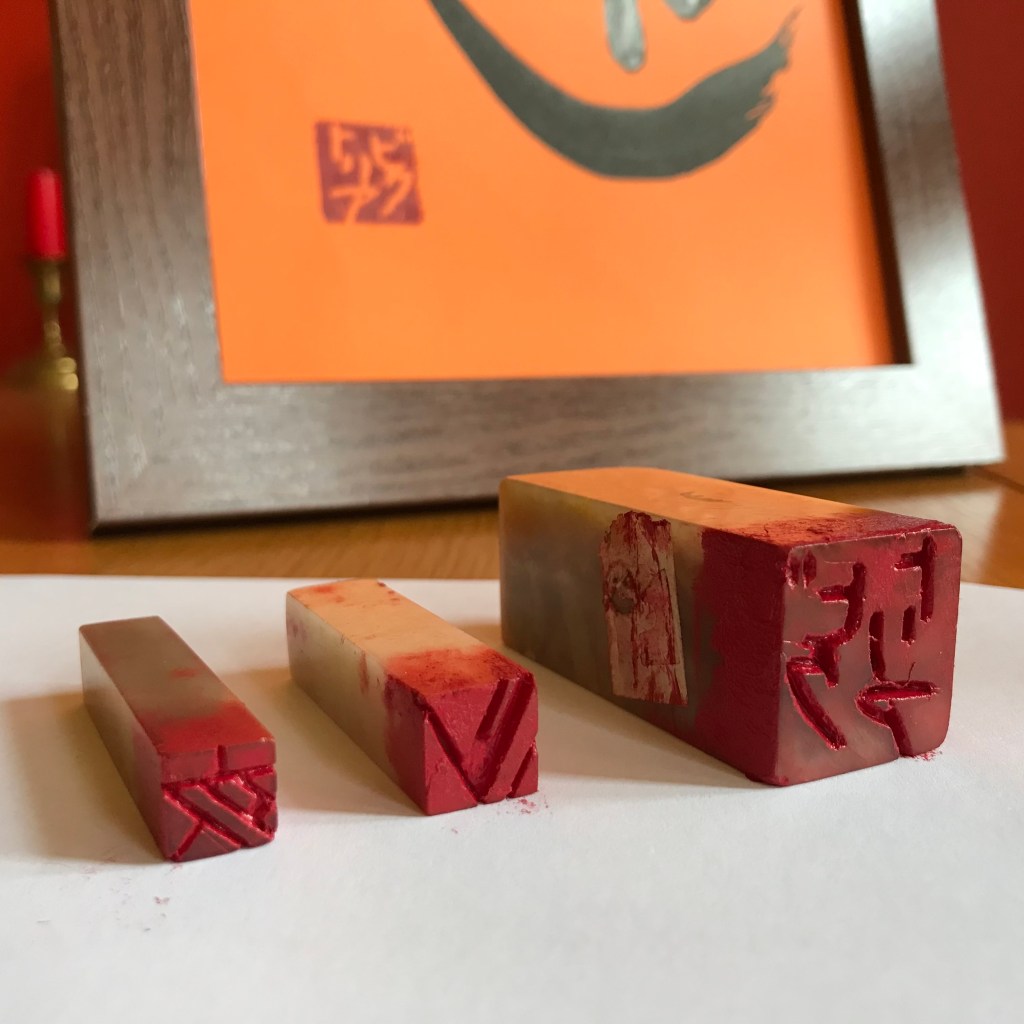 Three personal seals in front of a calligraphy work stamped with the largest seal.