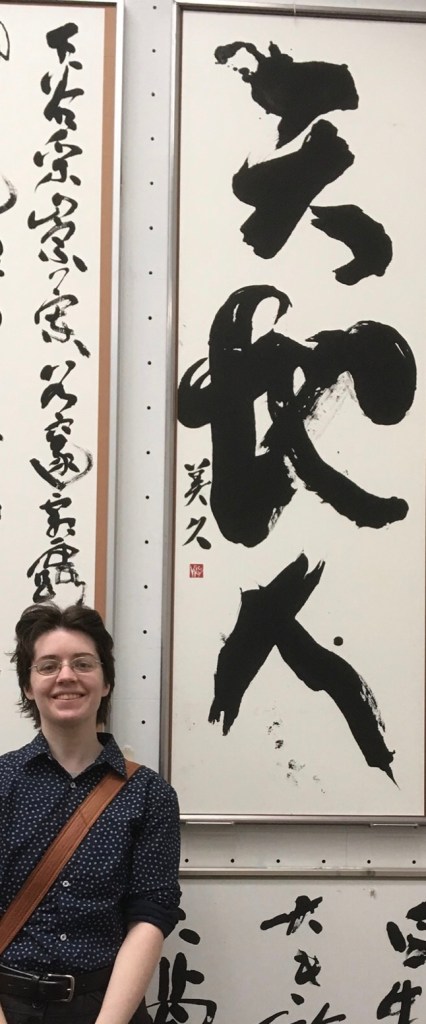 Me standing in front of my artwork on display at an exhibition.