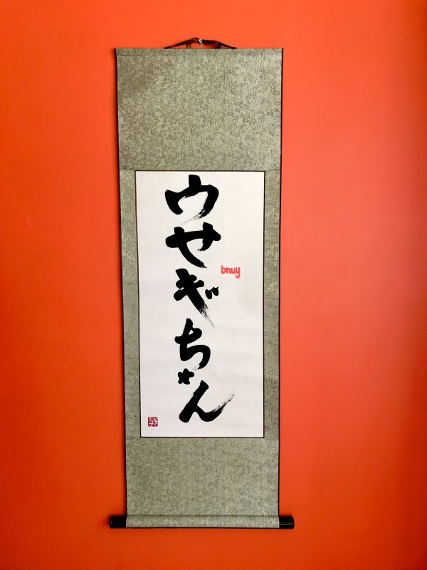 A hanging scroll with Japanese katakana characters.
