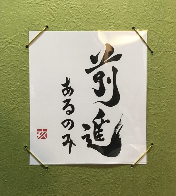 A Japanese calligraphy work. Black ink, white card, green frame.