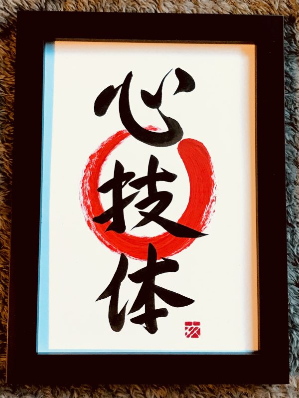 A Japanese calligraphy work of three kanji characters, black ink on white card, with a red enso, in a black frame.
