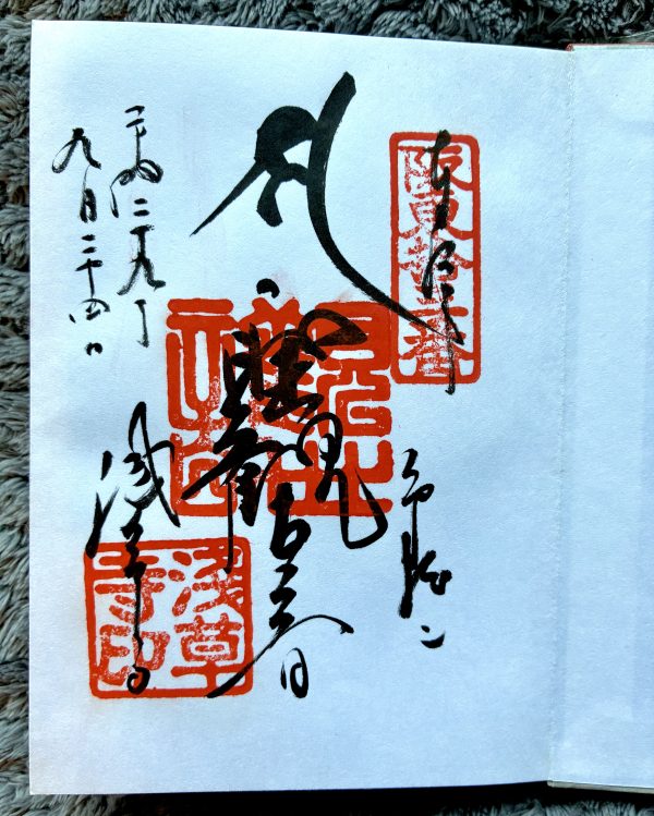 A page of a stamp book, covered in black Japanese calligraphy and red ink stamps