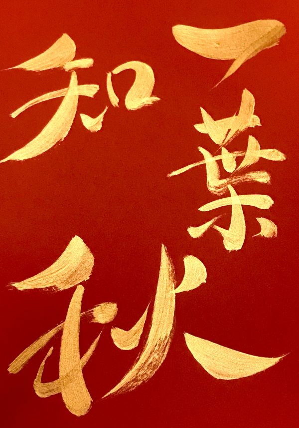 a 4-character Japanese calligraphy work, gold ink on red background.